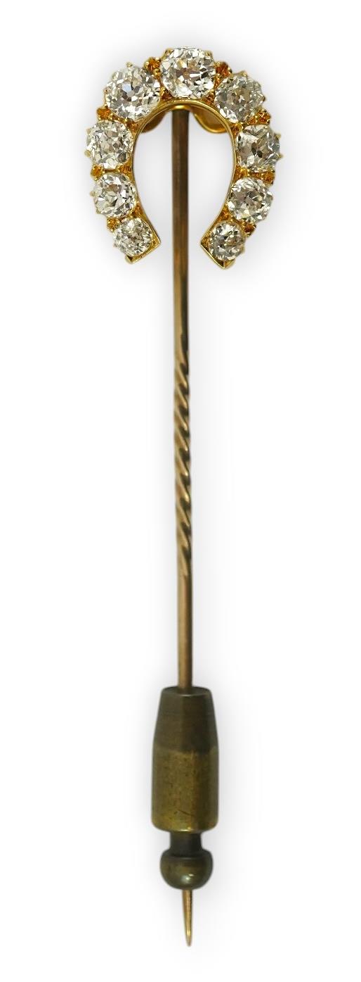 An early 20th century gold and nine stone graduated old cut diamond set horseshoe stick pin